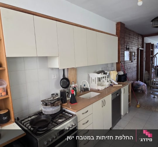 מטבח ביתי קים עם ארונות עליונים ותחתונים ומשטח עבודה